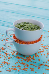 Two white cups of cereals close up. Scattered grains on blue wooden background.