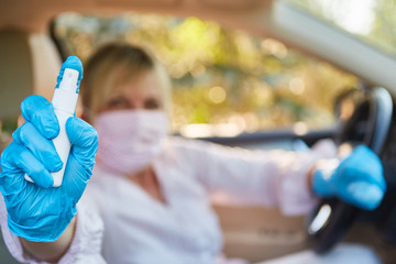 Frau im Auto mit Mundschutz und Desinfektionsmittel oder Reizgas