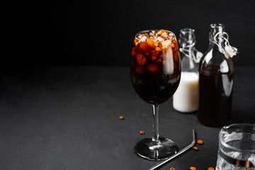 Cold brew coffee in a glass with metal straw on a dark background.Iced coffee	