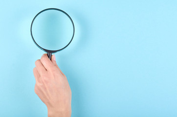Black magnifying glass on blue background.