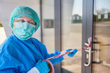 Mediziner befestigt Absperrung an Klinik bei Coronavirus Quarantäne