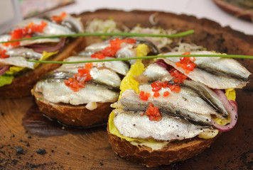 Sandwiches with anchovies on a vintage wooden board.