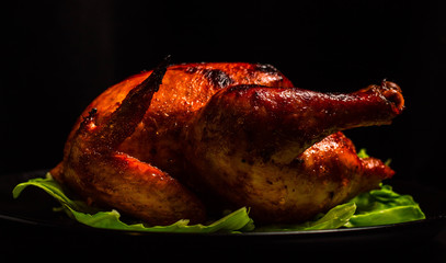 Fried Chicken with a crispy crust on a black plate, with a substrate of lettuce leaves. Just a shiny sour sweet chicken. Home cooking.