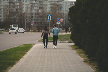 two friends are walking along a road in the city