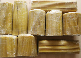 yellow wax candles, in plastic packaging, lie on a wooden surface, top view. Church, long candles....
