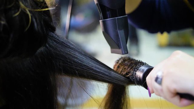 Slow motion of woman's brown hair being dried and straightened