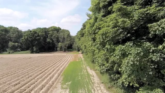 Fast aerial shot of French Napoleon soldiers walking in an open field surrounded by trees.