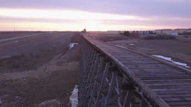 Retreating aerial: rickety old abandoned railway trestle at sunrise