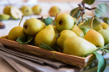 Fresh organic pears with leaves on white wooden background