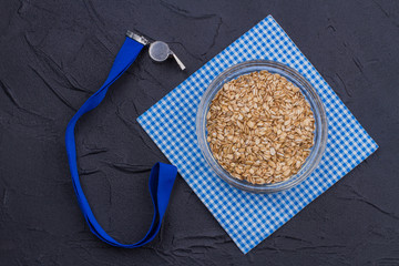 Healthy sport breakfast concept. Top view dry oatmeal porridge and whistle.