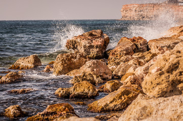 Fototapeta na wymiar Splitting waves against picturesque rocks in the sea