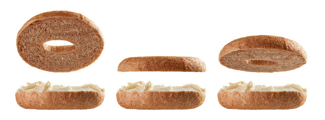 Halved bagels with cream cheese flying on white background