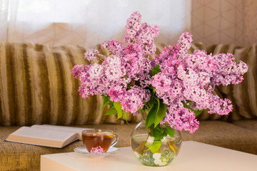 Obraz na płótnie Canvas Bouquet of pink lilacs in a vase on a book table.