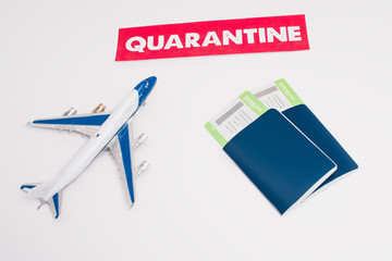 High angle view of toy near card with quarantine lettering and passports with air tickets on white background