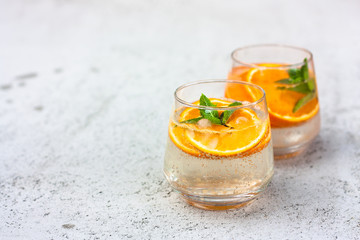 Lemonade, orange cocktail, cold, iced,refreshing summer drink in glasses with slices of orangeand mint. Front view. Selective focus