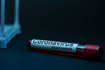 Obraz premium Selective focus of sample tube with coronavirus blood sample on dark