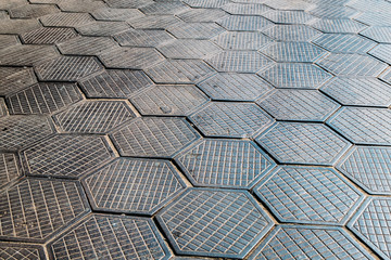 pattern of metal hexagons in a geometric paving slab in a parking lot