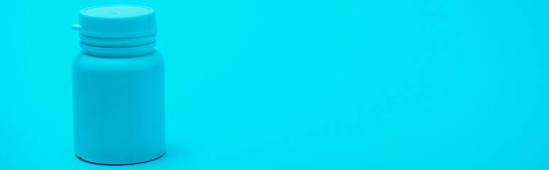 Horizontal image of white container with pills on blue background