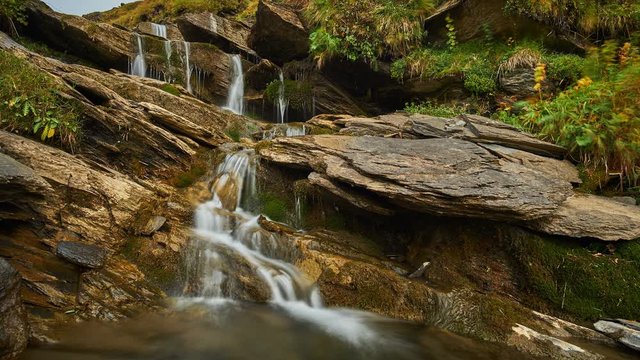 Time lapse of a small waterfall flowing into a rocky stream surrounded by trees in the mountains of Switzerland at Kleine Scheidegg, Grindelwald