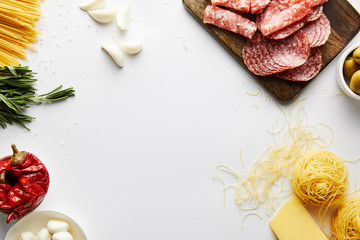 Top view of meat platter, pasta and ingredients on white background
