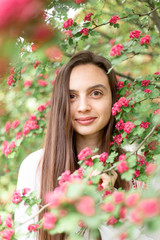 Naklejka premium Portrait of beautiful young smiling woman against the background of a blossoming pink flowers hawthorn tree 