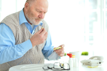 Portrait of sad sick senior man taking pills