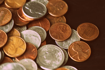 American cents are scattered on an old black wooden surface close-up. Retro style toned