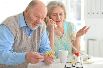 Portrait of sick senior couple calling to doctor
