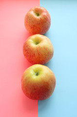 three yellow apples lie vertically on a pink, blue background. Summer is coming, vitamins, fruits, diet, healthy sweets. Place for text, inscriptions. fruits on a double background