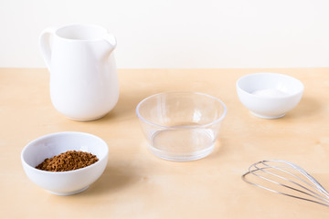 How to make coffee dalgona. Step by step photo instruction. Step 1 Preparation. Ingredients - instant coffee, sugar, water, milk and a whisk for whipping on a wooden background
