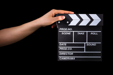 Human hand holding film clapper board isolated on black background
