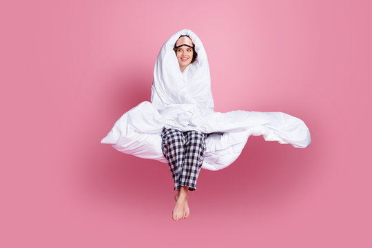 Full Size Photo Of Cheerful Lady Late Morning Sit Bed Hold Around Head Warm Blanket Look Empty Space Wear Mask White Plaid Pajama Pants Barefoot Isolated Pink Color Background