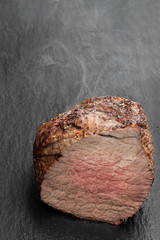 Roast beef on black stone background