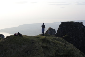 A hiker standing above a misty landscape. 