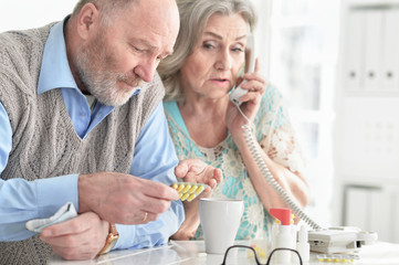 Portrait of ill senior couple at home calling doctor