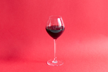 glass of red wine on red background