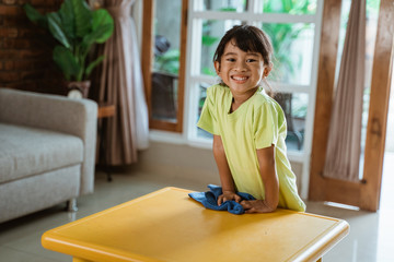 happy young kid smiling to camera while doing house cleaning