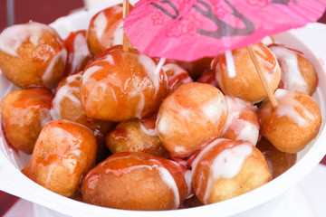 Fresh round small donuts during carnival or fast food festival, glazed with dark and white chocolate