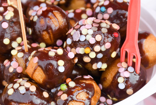 Fresh round small donuts during carnival or fast food festival, glazed with dark and white chocolate