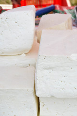 A variety of wheels of cheese seasoned with herbs for sale at the deli counter in the supermarket.