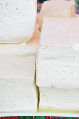 A variety of wheels of cheese seasoned with herbs for sale at the deli counter in the supermarket.