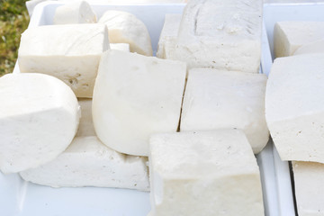 A variety of wheels of cheese seasoned with herbs for sale at the deli counter in the supermarket.