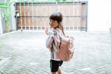 young kid waving goodbye before leaving to school in the morning