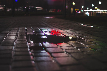 a small puddle on the pavement. night in the city
