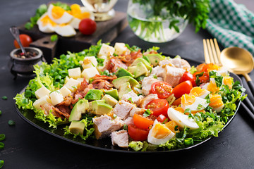 Healthy cobb salad with chicken, avocado, bacon, tomato, cheese and eggs. American food.