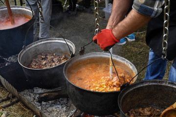 Very large cauldron cooking food during campfire. Cooking in a pot on the fire. Camping concept