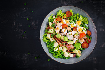 Healthy cobb salad with chicken, avocado, bacon, tomato, cheese and eggs. American food. Top view....