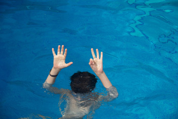 the boy under the water withdrew his palms and shows his fingers that he is eight years old