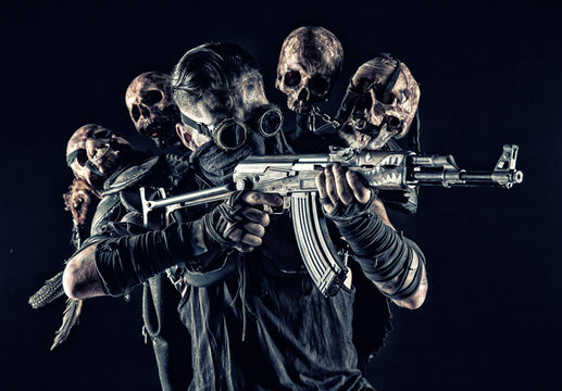 Post apocalyptic survivor, radioactive zone stalker, crazy serial killer or maniac in glasses and skulls on shoulders, with automatic rifle