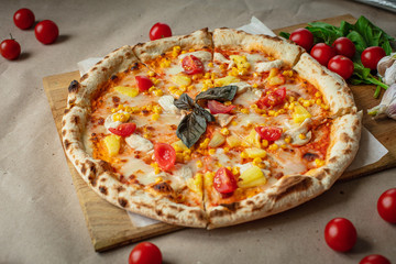 Pizza made on wood and Kraft paper, around tomatoes, herbs and garlic. Lunch prepared at home